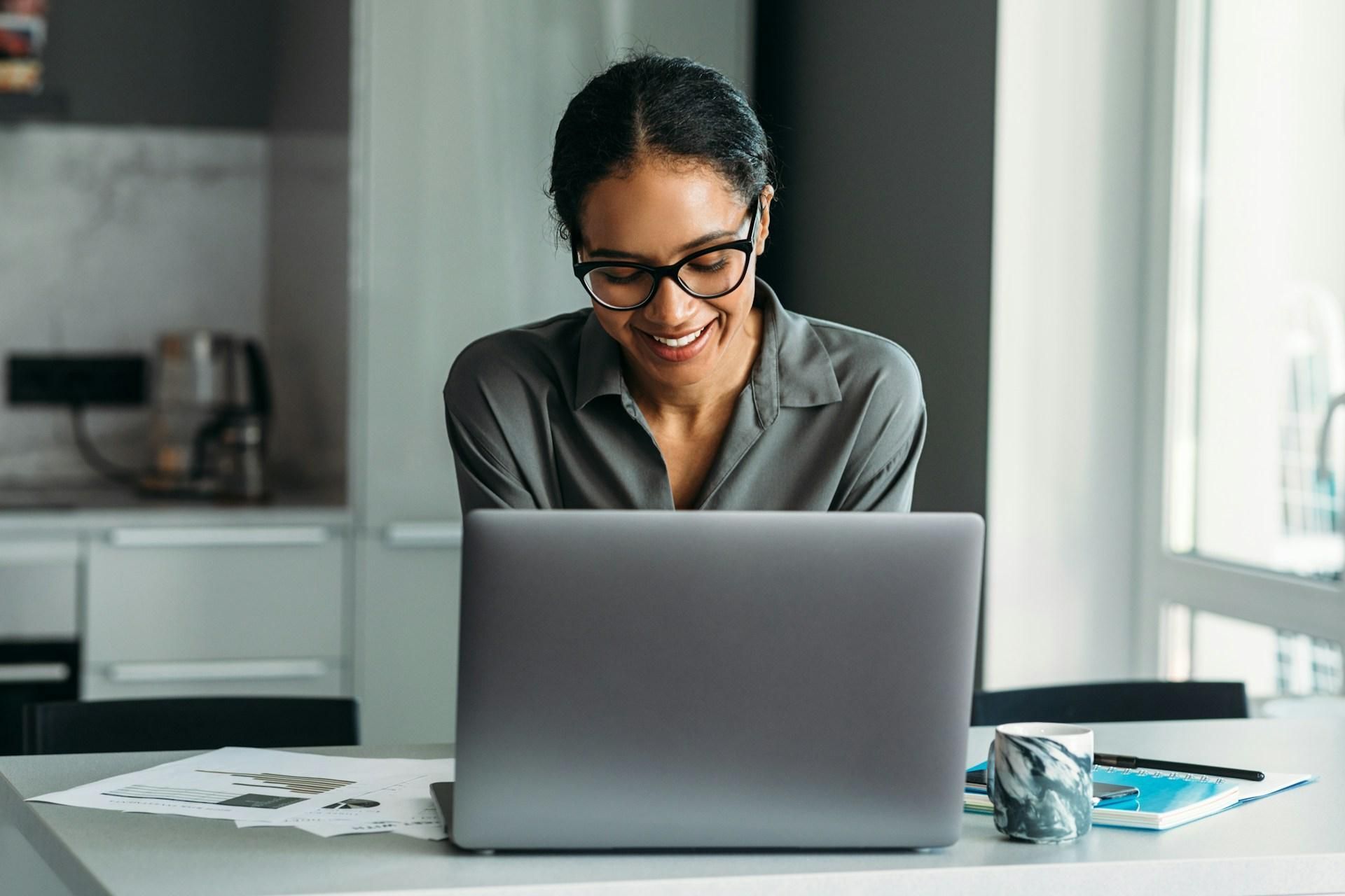 Job seeker smiling at her laptop while using AI job search tools to optimize her resume and applications