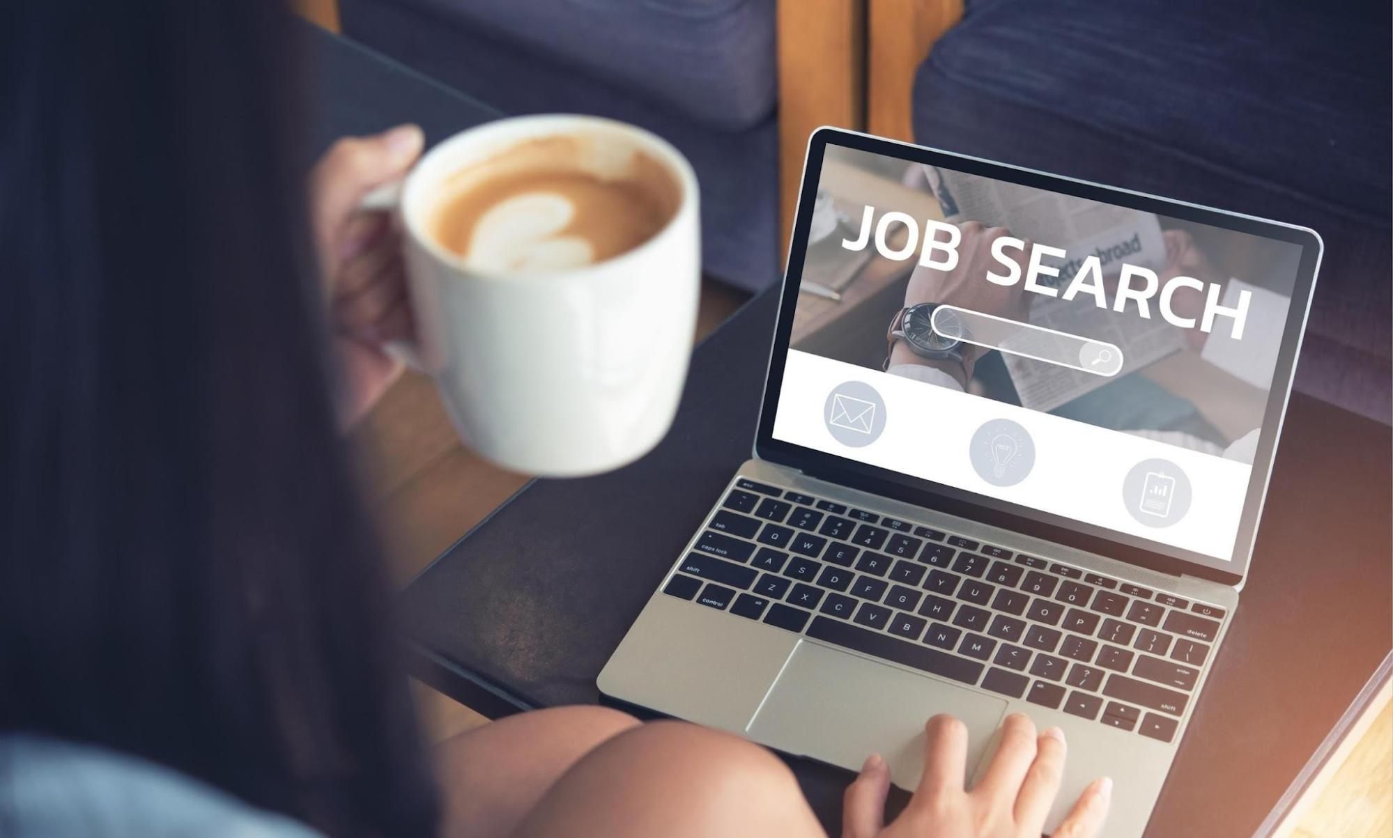 Person browsing job search website with coffee