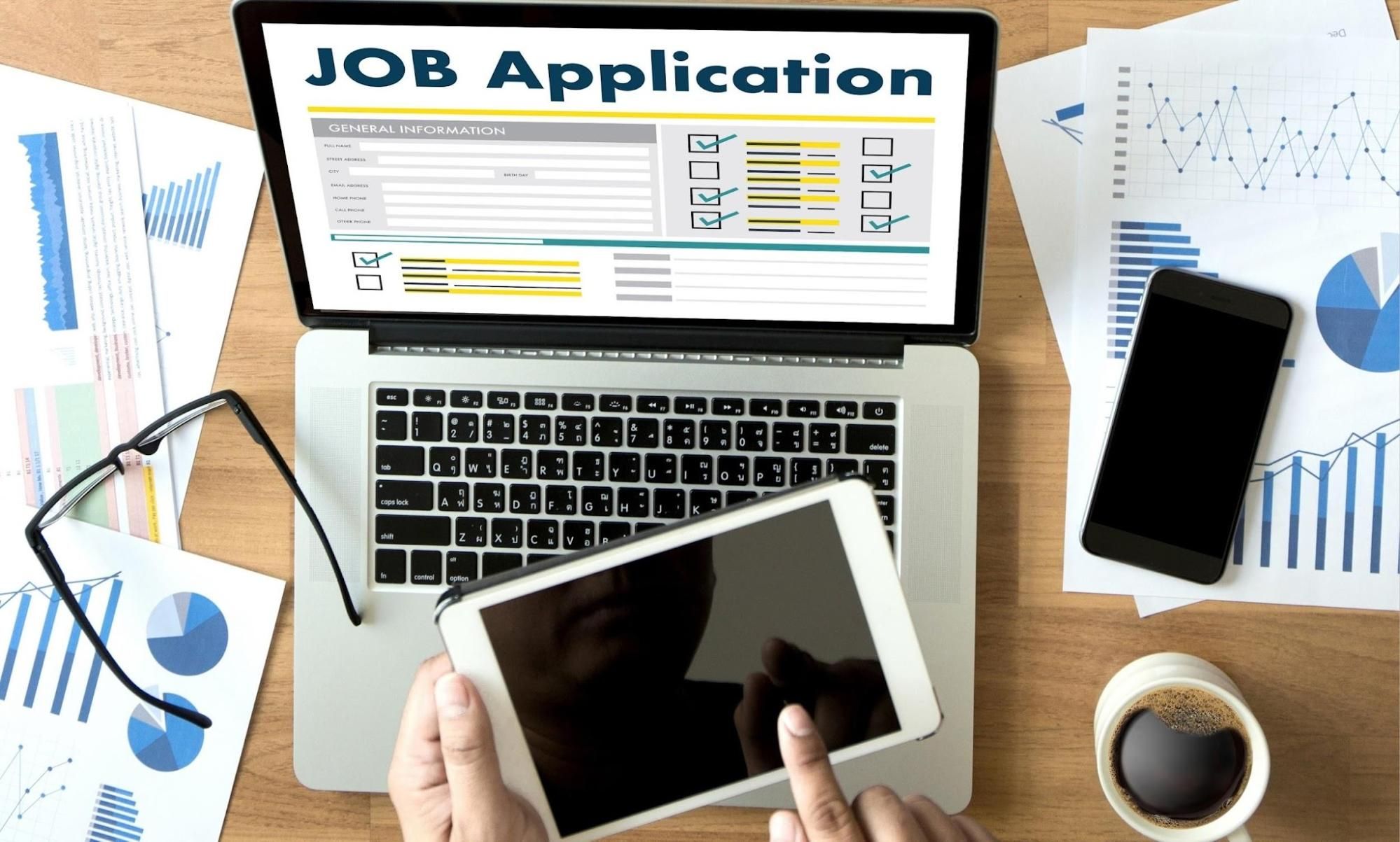 Person-using-tablet-beside-job-application-laptop