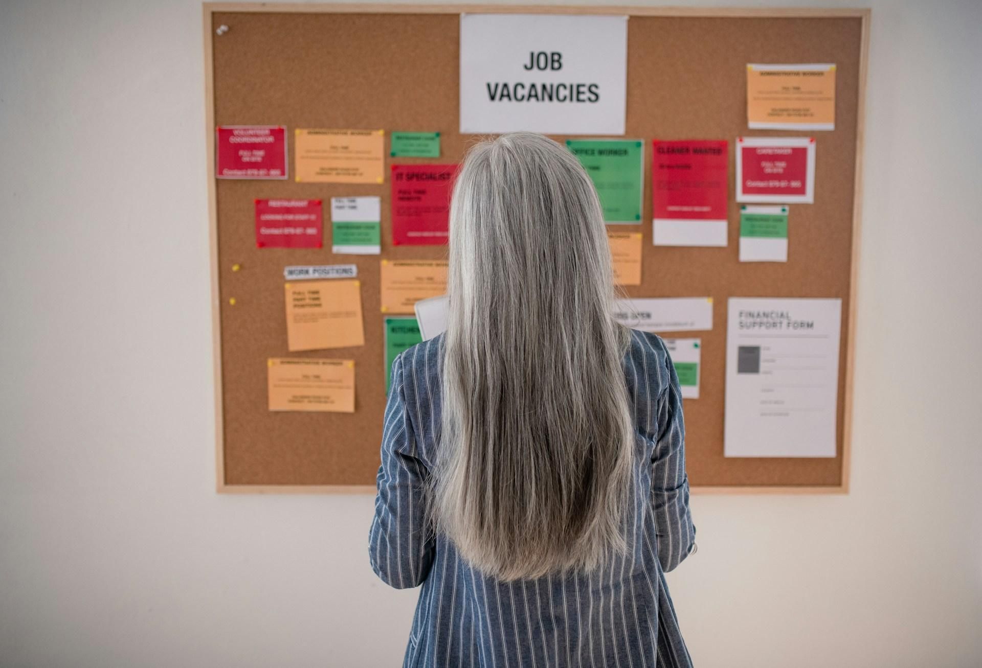 Students scanning a job vacancy notice board with internship and work position listings pinned up
